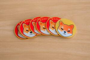 One gold Shiba inu SHIB ahead followed by red shiba inu coins arranged together, close up. photo