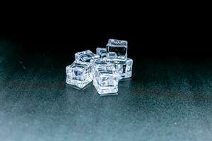 Many ice cubes clustered together with a black background backdrop. photo