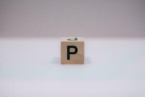 Wooden block written P with a white background, education concept, close up. photo