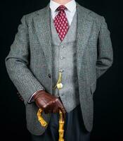 retrato de hombre en tweed traje y cuero guantes participación sombrilla. Clásico estilo y retro Moda de clásico Inglés Caballero. foto