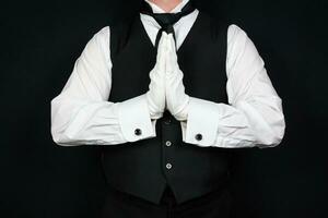 retrato de mayordomo en negro chaleco y blanco guantes participación manos en oración. Servicio industria y profesional el respeto y cortesía. foto