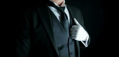 aislado de cerca de mayordomo en oscuro traje y blanco guantes en pie a digno atención. Servicio industria y profesional hospitalidad. foto