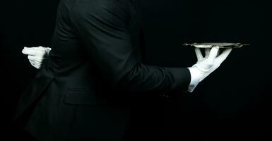 Portrait of Elegant Butler or Waiter in Dark Suit and White Gloves Holding Serving Tray. Service Industry and Professional Hospitality. photo