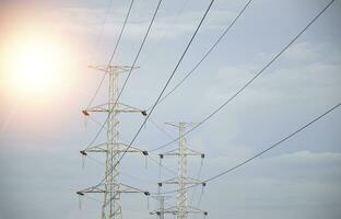 High voltage towers at sunset background. Power lines against the sky photo