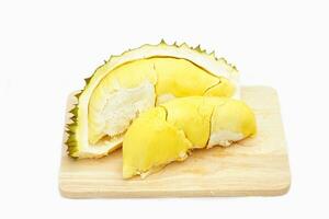 Yellow-fleshed durian pulp, soft and firm, with an appetizing aroma, beautifully arranged on a wooden cutting board on a white background. Soft and selective focus. photo
