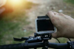 Male hand adjusting action camera on bicycle photo