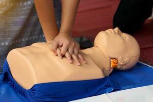 asiático joven rojo cruzar estudiantes práctica cpr con un maniquí durante un formación curso en Ayudar pacientes quien son muriendo a respirar espalda a respiración. o respiración lata circular normalmente. foto