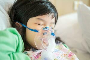 Sick little asian girl inhalation with nebulizer for respiratory treatment photo