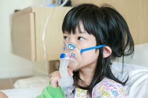 enfermo pequeño asiático niña inhalación con nebulizador para respiratorio tratamiento foto