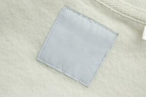 Blank white laundry care clothes label on fabric texture background photo