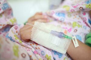 Close up child hand with saline IV solution in hospital photo