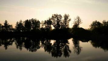 de zon instelling over- een meer met bomen video