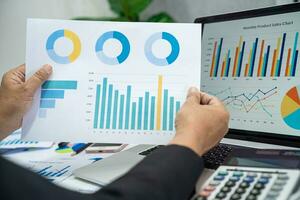 Asian accountant working and analyzing financial reports project accounting with chart graph in modern office, finance and business concept. photo