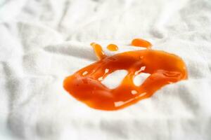 mancha de salsa de tomate sucia o ketchup en tela para lavar con detergente en polvo, limpieza del concepto de tareas domésticas. foto