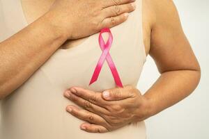 Asian woman patient checking and worry her breast, Breast Self Exam or BES, symbol of World Breast Cancer Day. photo