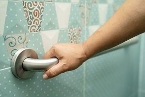 Asian elderly woman use bathroom handle security in toilet, healthy strong medical concept. photo