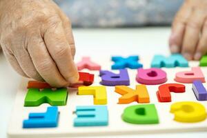 Alzheimer disease AD, Asian elderly woman patient suffering from dementia learn practical motor skills rehabilitation. photo