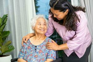 Caregiver help Asian senior woman on wheelchair with love at home. photo