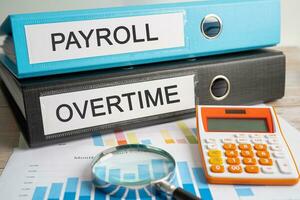 Payroll, Overtime. Binder data finance report business with graph analysis in office. photo