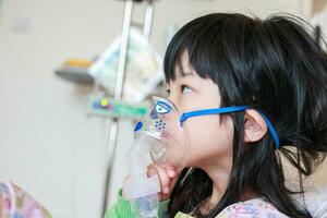 enfermo pequeño asiático niña inhalación con nebulizador para respiratorio tratamiento foto