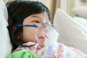 enfermo pequeño asiático niña inhalación con nebulizador para respiratorio tratamiento foto
