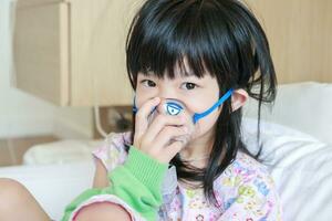 Sick little asian girl inhalation with nebulizer for respiratory treatment photo