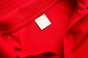 Blank white laundry care clothes label on red shirt fabric texture background photo