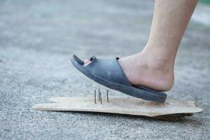 de cerca hombre vestir Zapatos es pisar en oxidado metal uña en madera. concepto, inseguro , riesgo para peligroso tétanos. ser Cuidado y Mira alrededor durante caminando en el piso o riesgo lugares. accidente foto