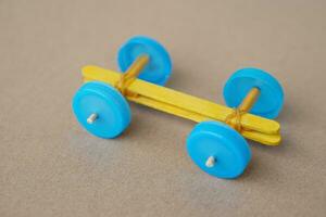 Handmade toy racing car made from ice cream sticks and bottle caps. Concept, Recycling kids toy. Easy to do, creative DIY craft that kids can do. Fun lesson photo