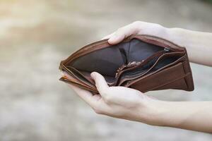 Close up hands hold and open empty and torn wallet with no money. Concept, poor, bad economic crisis. Financial problems. Broke or less money at the end of month. Pay day. photo