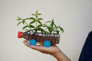 Close up hand hold DIY car which grow plants, made from plastic bottle and caps. Concept, Gardening from recycle crafts. Reduce, reuse and recycle plastic garbage photo