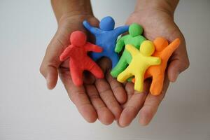 Close up hands holds colorful plasticine people. Human figures from plasticine sculpture.  Concept, friendships, partnerships and relationships between people. Sculting enhance imagination. photo