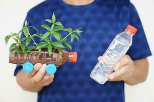 Close up man holds DIY car which grow plants, made from plastic bottle and caps. Concept, Gardening from recycle crafts. Reduce, reuse and recycle plastic garbage photo