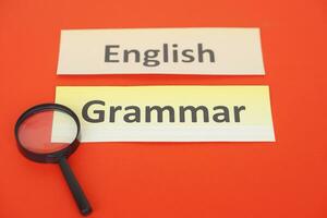 Word cards English Grammar, magnifying glass on red background. Concept, language learning. Find English grammar stucture. Education. School subjects. photo