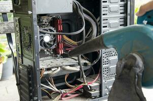 Photograph of a technician blowing dust from a computer photo