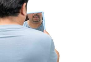 barbado hombre mirando en el espejo para piel etiquetas o acrocordón en su cuello foto