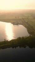 Vertical video of aerial view over a lake at sunset