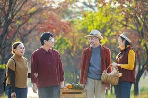 Happy Asian farmer family with senior parent are carrying produce harvest with homegrown organics apple, squash and pumpkin with fall color from maple tree during autumn season for agriculture usage photo