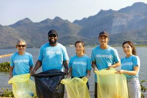 equipo de joven y diversidad voluntario trabajador grupo disfrutar Caritativo social trabajo al aire libre en limpieza arriba basura y residuos separación proyecto a el río playa foto