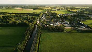 aéreo Visão do uma canal e casas dentro uma verde rural área video