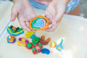 Child playing with colorful clay making animal figures. closeup on hands photo