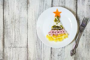 Navidad árbol desde un ensalada olivier en plato en un blanco de madera mesa. parte superior ver con un Copiar espacio foto