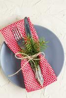 Christmas menu background with fork knife napkin and fir tree brunch on white table. top view photo