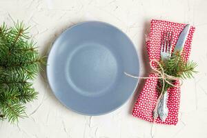 Christmas menu background with fork knife napkin and fir tree brunch on white table. top view photo