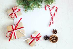 Clear paper laying with candy cane, Christmas tree branches and gifts photo