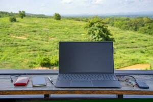 laptop computer and device for working digital nomad put on table, background top view of resort garden on mountain in the countryside,concept of digital nomad working photo