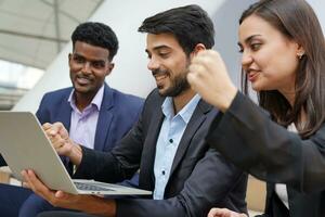 multiracial young business people in suit giving hands fist up to laptop  for congratulations of successful business when meeting over laptop photo