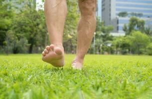 senior man barefoot walking on grasses in the park,concept for homeopathy lifestyle,activity, benefits in elderly to increase balance awareness of joint position and movement making it easy to walk photo