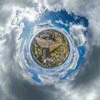 tiny planet in sky with clouds overlooking old town, urban development, historic buildings and crossroads. Transformation of spherical 360 panorama in abstract aerial view. photo