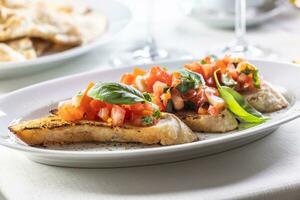 Detail of bruschetta on sourdough bread with chopped tomatoes and fresh basil leaves photo